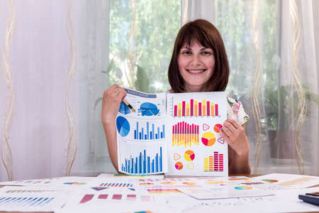 Beautiful analyst with business graphs in office