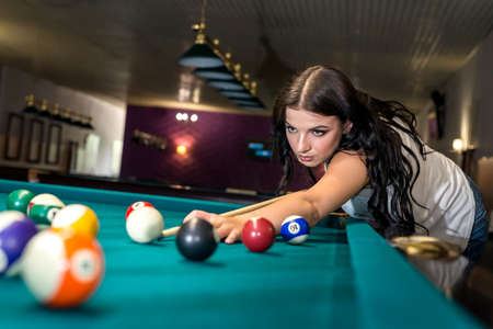 Beautiful brunette woman concentrated on billiard game