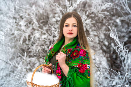 Woman in green shawl holding basket in winter park