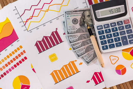 Dollar banknotes with pen and calculator on business graphs