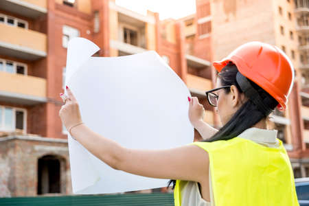 Beautiful woman on construction site looking at blueprint