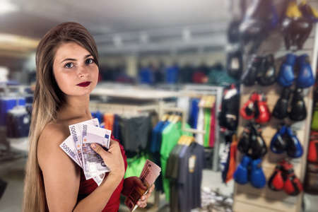 Shopping in sport equipment store, woman with euroの写真素材