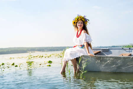 Beautiful girl in national dress in boat on lakeの写真素材