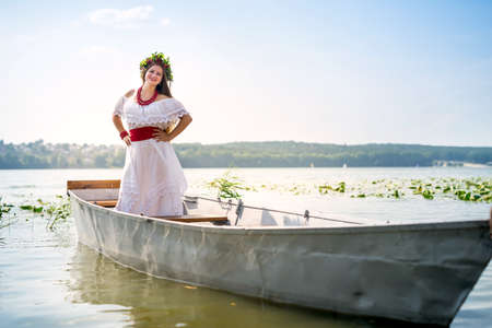Beautiful girl in national dress in boat on lakeの写真素材
