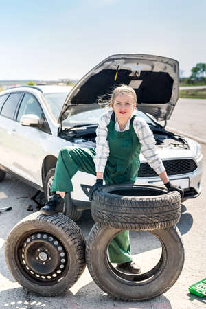Woman mechanic posing with spare wheel and tiresの写真素材