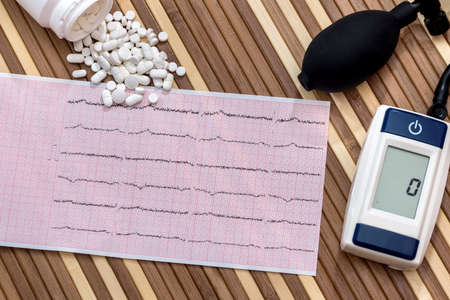 Pills on cardiogram with electronic tonometer, closeup