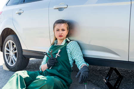 Tired mechanic with spare wheel and different tools