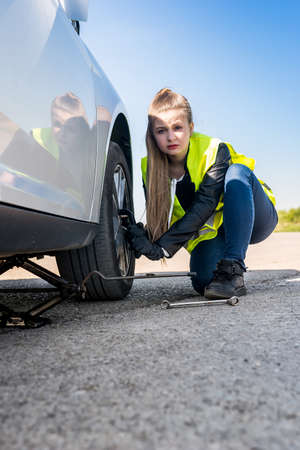 Woman changing damaged wheel and fixing it
