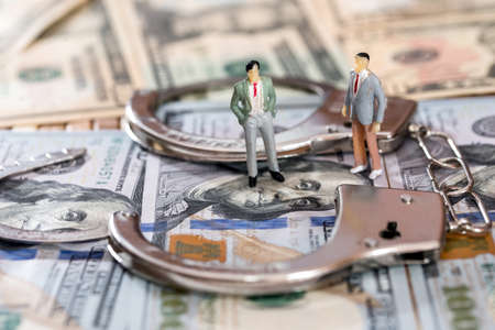 Toy figures with handcuffs on dollar banknotes