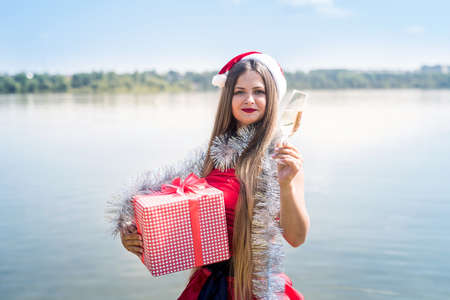Attractive woman with gift box and champagneの写真素材