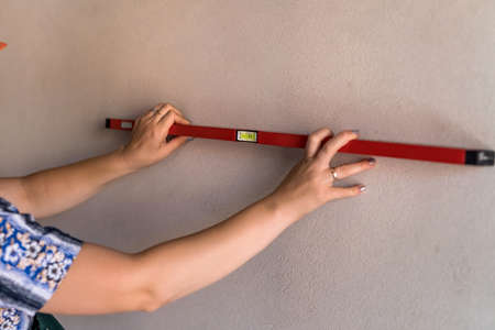 Female hands with water level tool close up