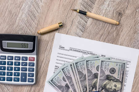 Dollar, calculator and pen with 1040 tax formの写真素材
