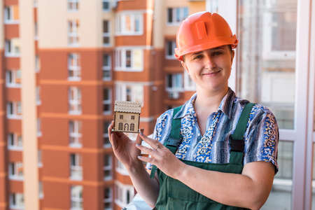 Woman showing wooden house model on balconyの写真素材