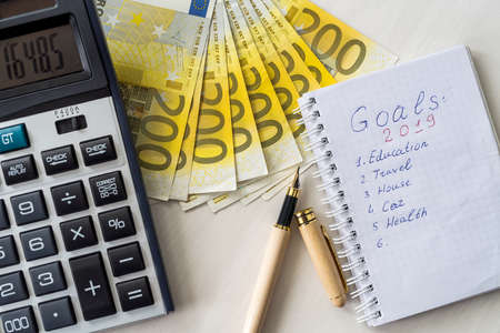 Euro banknotes with calculator and notepad with goalsの写真素材