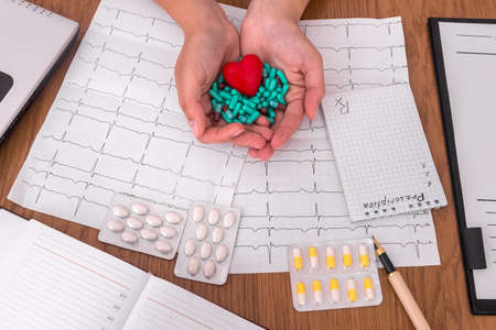 Female hands with green capsules and red heart
