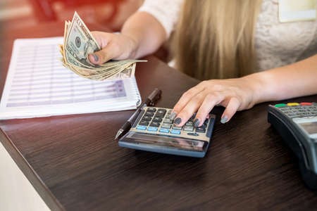 Young woman calculates dollars on calculator