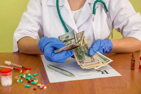 Doctor's hands counting dollar banknotes, close upの写真素材