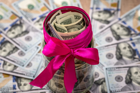 jar with dollars with a pink ribbonの写真素材