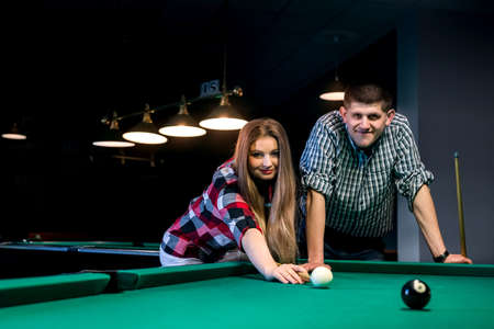 Young and beautiful couple playing billiard in barの写真素材