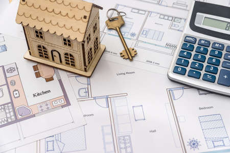 Wooden house model and key on house plan drawingの写真素材