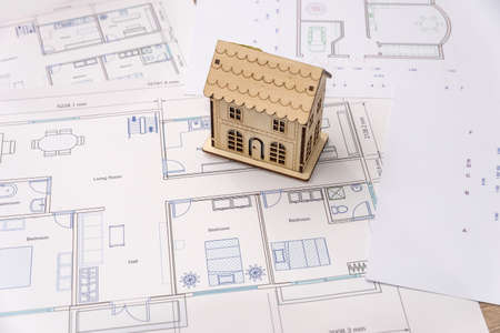 Wooden house model with blueprint and laptop
