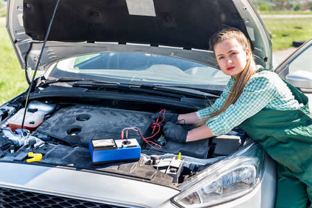 Mechanic - woman tests motor with tester
