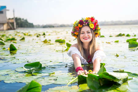 Beautiful girl with water lily standing in waterの写真素材