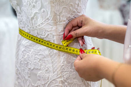 Measuring yellow tape with female hands and wedding dressの写真素材