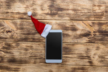 Smartphone with santa hat on wooden deskの写真素材