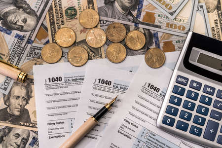 1040 tax form with golden coins and calculatorの写真素材