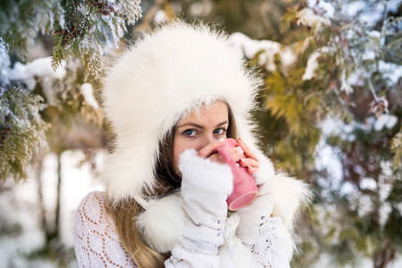 Young woman with cup of coffee in winter park