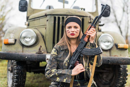 Woman in military uniform with rifle and carの写真素材
