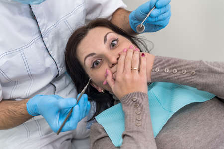 Woman in dentistry closing mouth with handsの写真素材