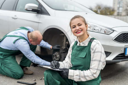 Two mechanics examining brake disk in carの写真素材