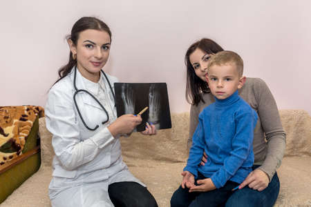 Mother with son and doctor orthopedician holding x-ray
