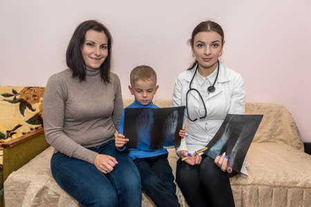 Doctor with x-ray and little boy with mother
