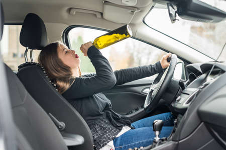 Woman drinking alcohol while driving a car