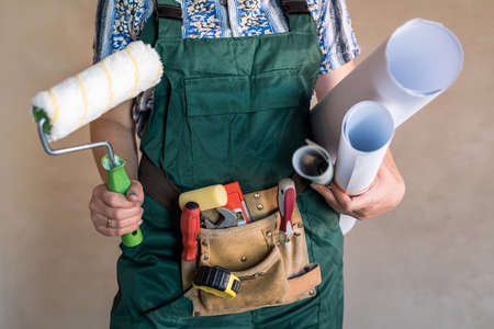 Builder belt with tools and hands with blueprintsの写真素材