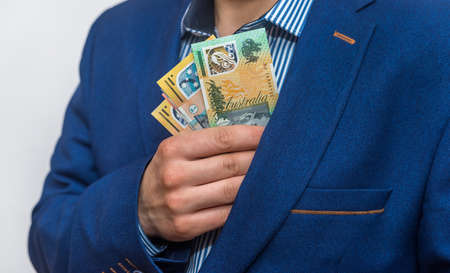 Male hand hiding australian dollar banknotes into pocketの写真素材