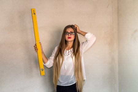 Portrait of worried woman holding water level toolの写真素材