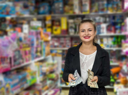 Woman counting dollar banknotes in toy shopの写真素材