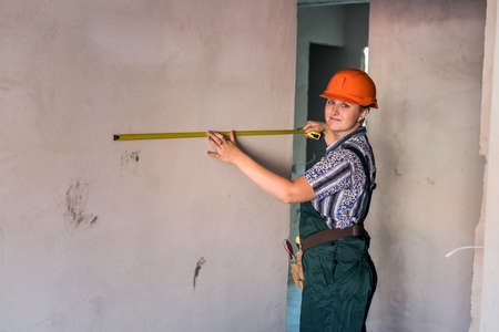 Woman in helmet and protective uniform posing with meterの写真素材