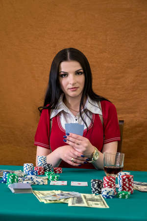 Beautiful brunette in casino holding playing cards