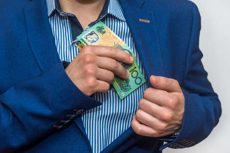 Male hand hiding australian dollar banknotes into pocketの写真素材