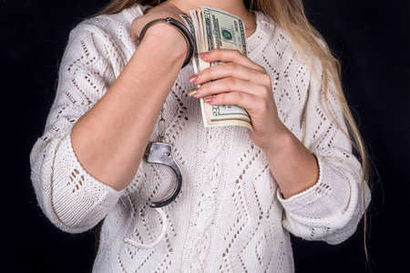 woman holding dollar bills in handcuffs