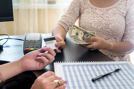 Female hands with credit card, terminal for payment and dollars