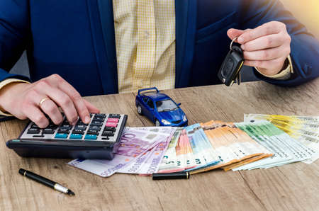 The businessman keeps the keys from the machine and count the euro into calculator