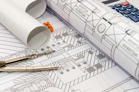 Engineers drawing with compass, calculator and rollsの写真素材