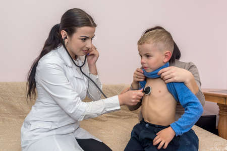 Woman pediatrician listening boy's breathing in hospital