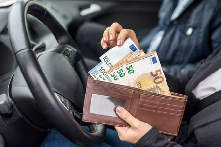 Woman holding wallet with euro sitting in carの写真素材